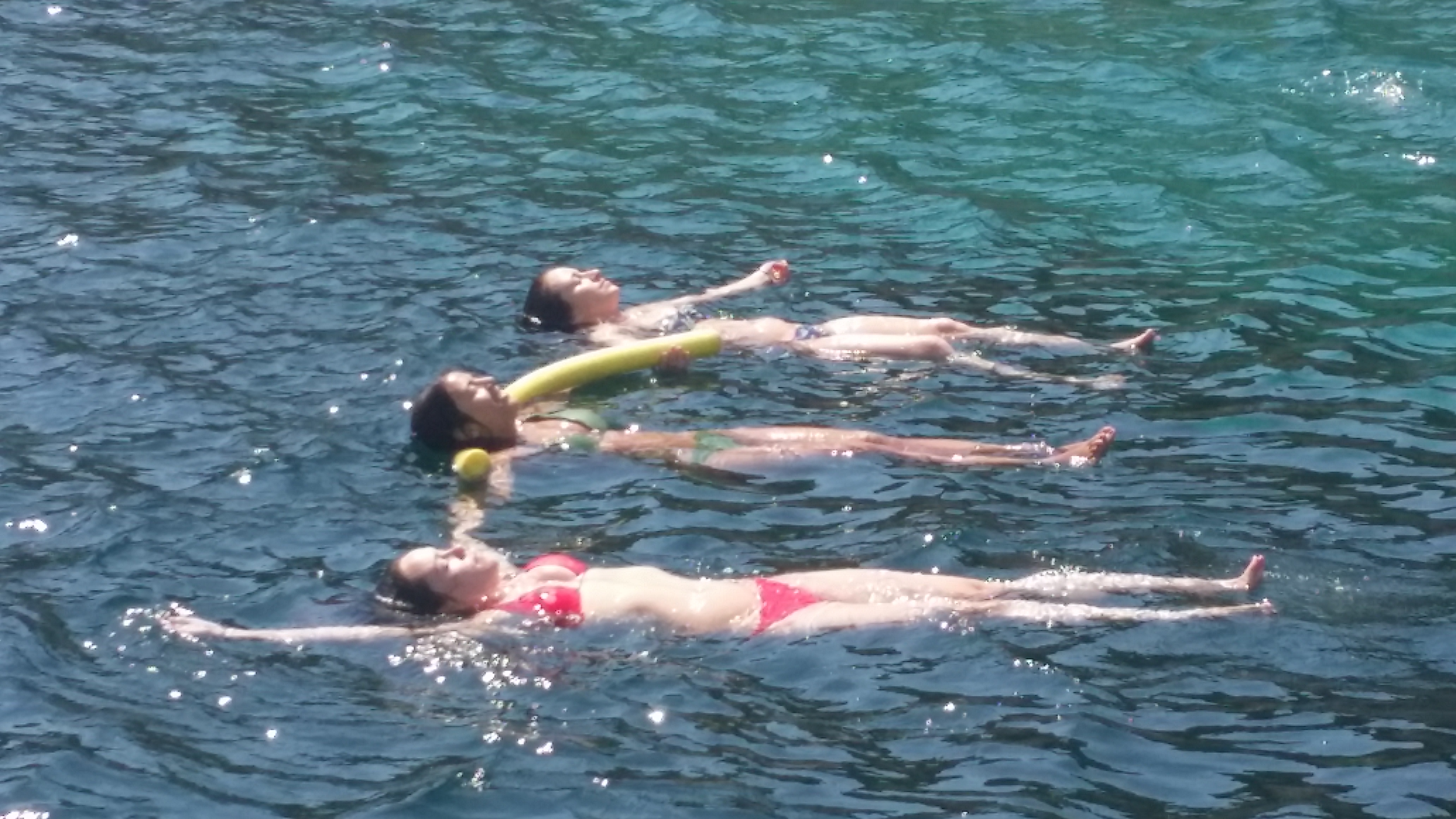 Three girls in a row floating on the sea